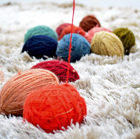 Voici un aperçu de divers fils de laine colorée avec des teints différents. Ils sont roulés en boules et prêts à être posés sur le métier à tisser.